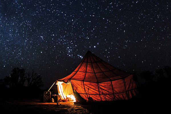 Ein echtes Highlight: erleuchtetes Zelt unter Sternenhimmel in der Nacht in der Sahara